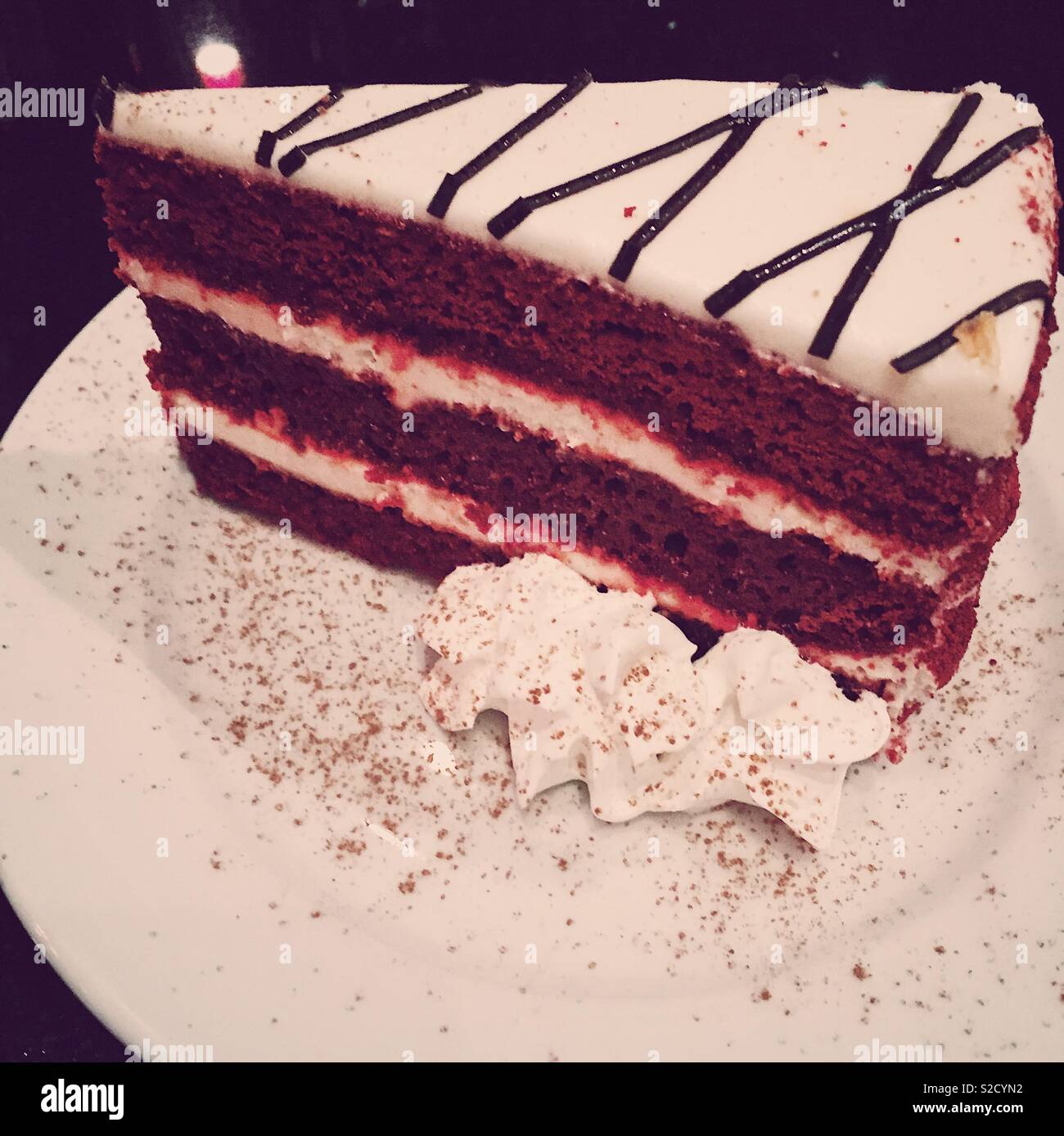 Großes Stück Red Velvet Cake mit Cream Cheese frosting und Rahm Stockfoto