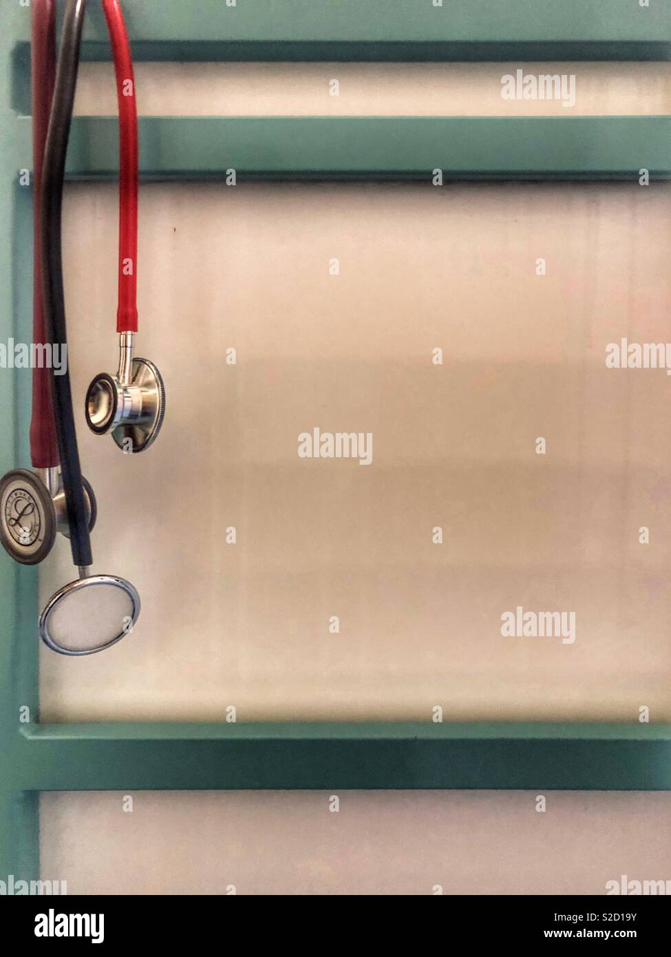 Rot und Schwarz Stethoskope hängen an der Ecke der weißen und grünen klinische Krankenhaus Trolley Stockfoto