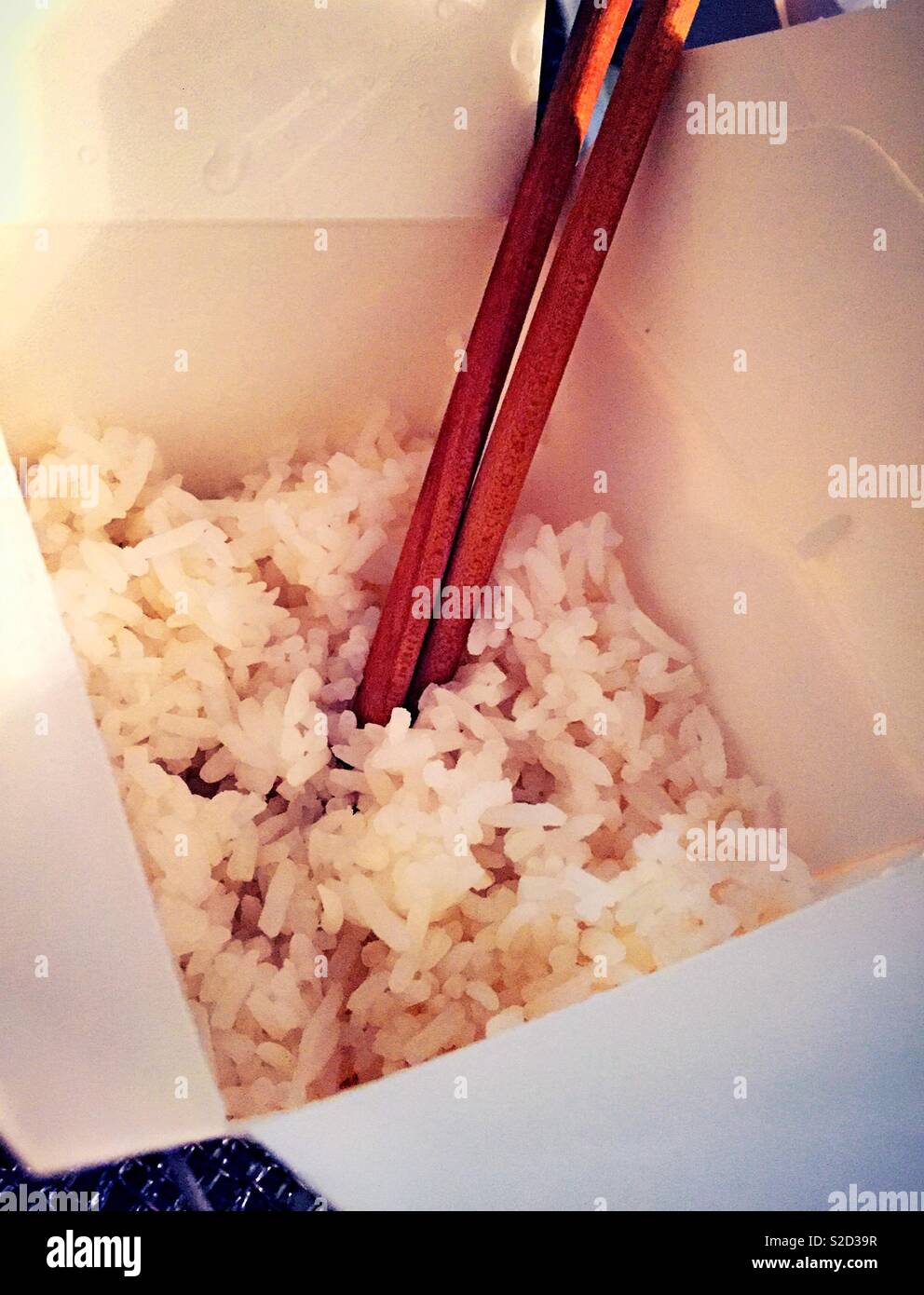 Karton von Reis mit Stäbchen aus dem Chinesischen takeout Mahlzeit, NYC, USA - Smartphone-aufgenommenes Stockfoto