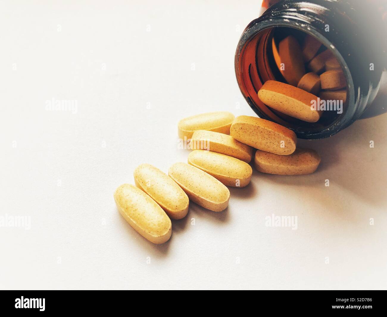 Gesundheitswesen und Medizin. Stapel der generischen Tabletten verschütten aus einem braunen Glasflasche auf einem weißen Hintergrund, Nahaufnahme, selektiven Fokus mit kopieren. - Smartphone-aufgenommenes Stockfoto