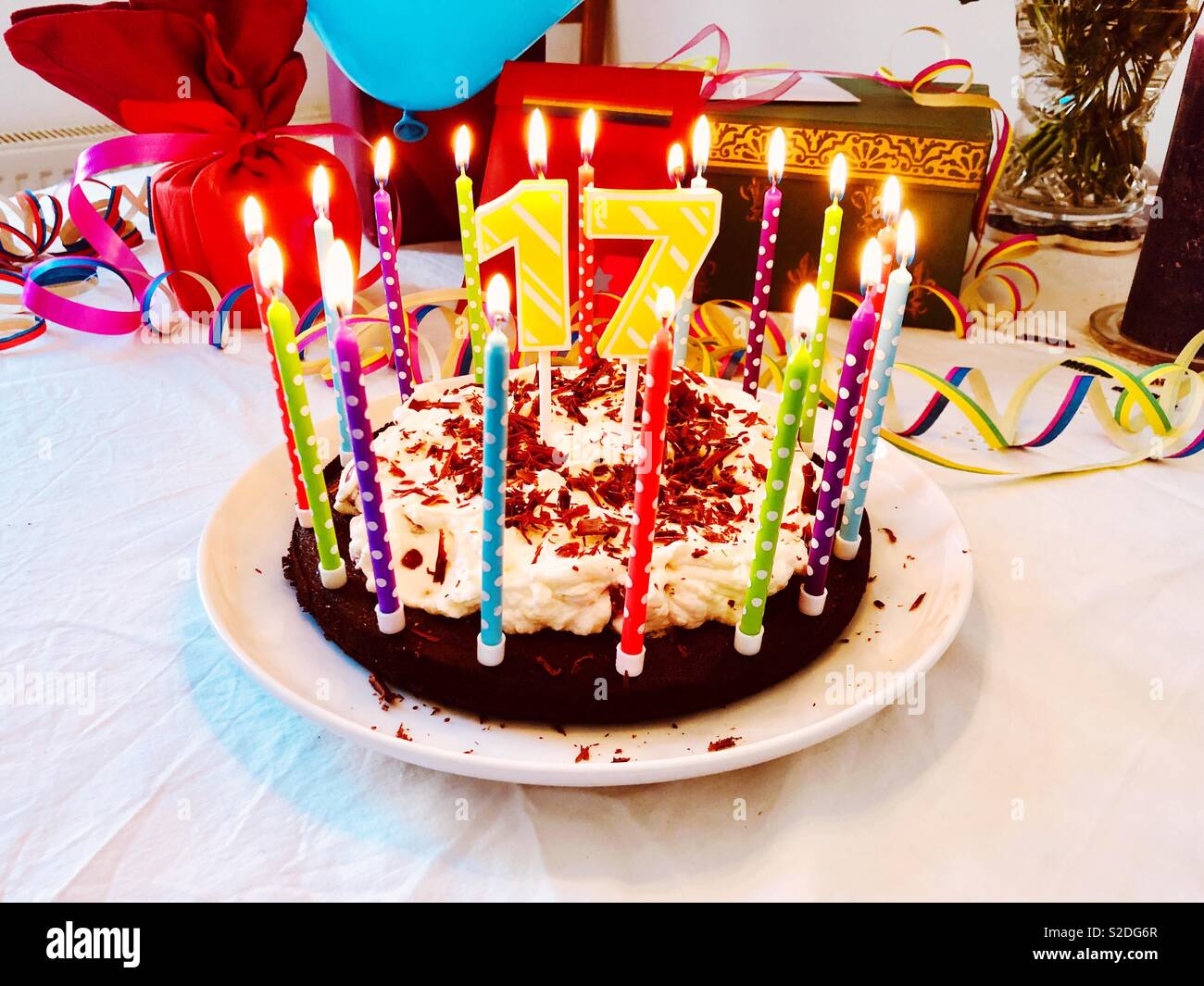 Geburtstag Kuchen Fur Einen 17 Geburtstag Mit Brennenden Kerzen Und Bunte Dekoration Auf Einem Geburtstagstisch Mit Geschenken Im Hintergrund Stockfotografie Alamy