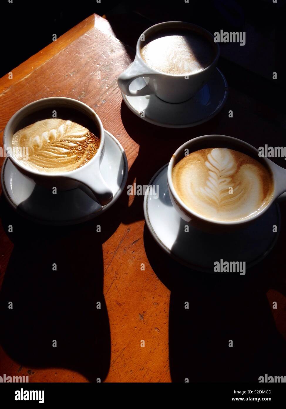 Drei Keramik Tassen Kaffee auf einem Holztisch mit Licht und Schatten, dunklen Vignette Stockfoto