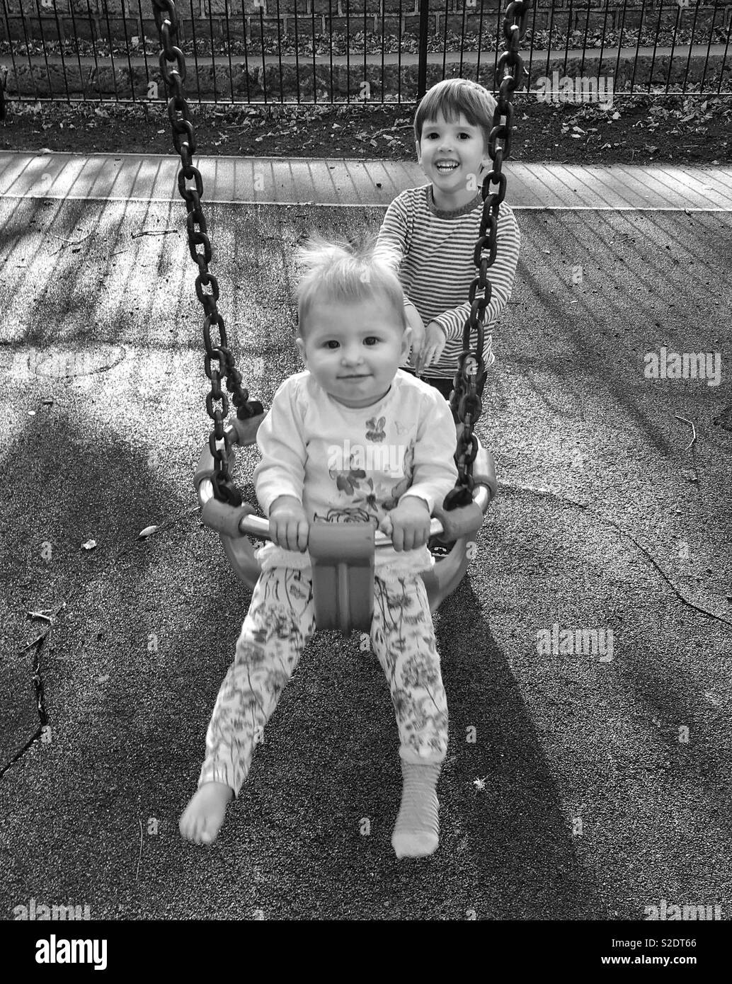 Junge seine Schwester auf der Schaukel im Park Stockfoto
