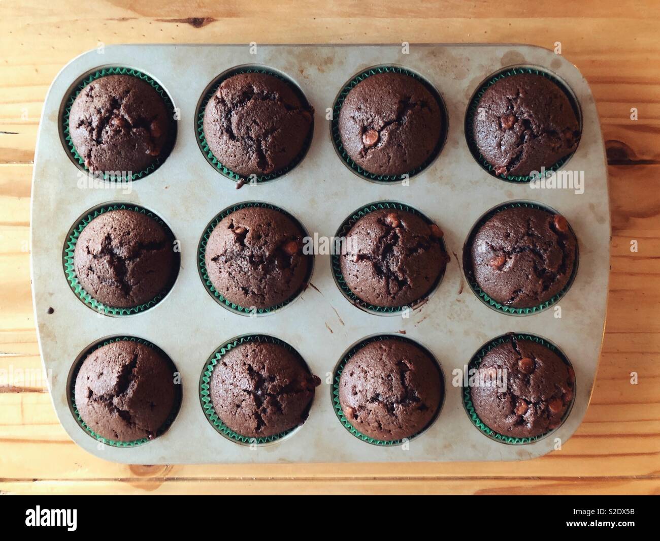 Flach auf hausgemachte Schokolade Chip zucchini Muffins in einem Metallauflagefach auf hölzernen Tisch - Smartphone-aufgenommenes Stockfoto