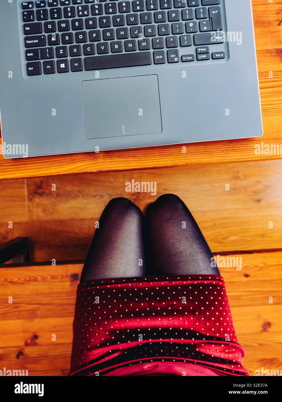 Frau mit einem Notebook Computer auf einem Schreibtisch aus Holz Stockfoto