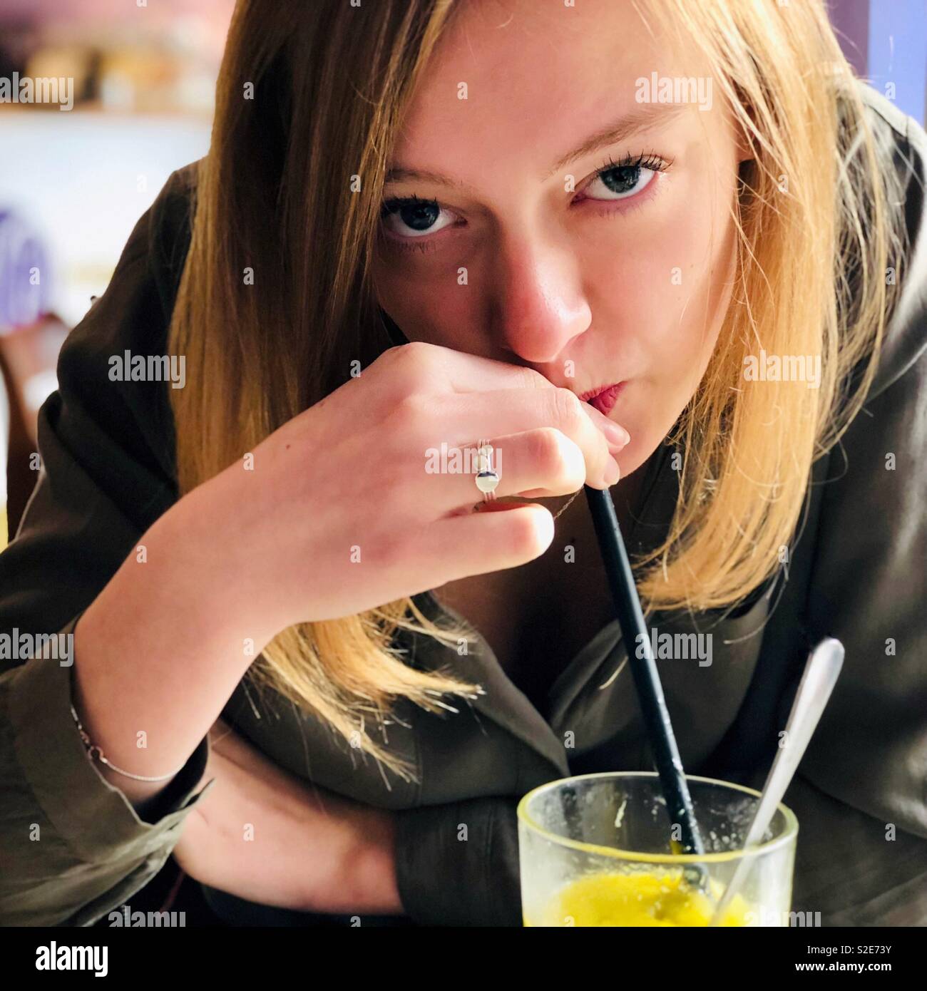 Nahaufnahme, Porträt einer schönen jungen Frau trinkt ein Smoothie mit einem Strohhalm. Stockfoto