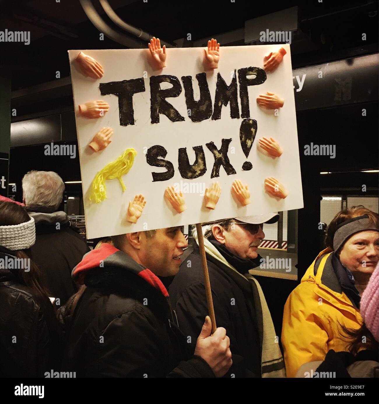 Mann in der U-Bahn auf dem Weg zu der Frau März holding Anti Trump Zeichen Stockfoto