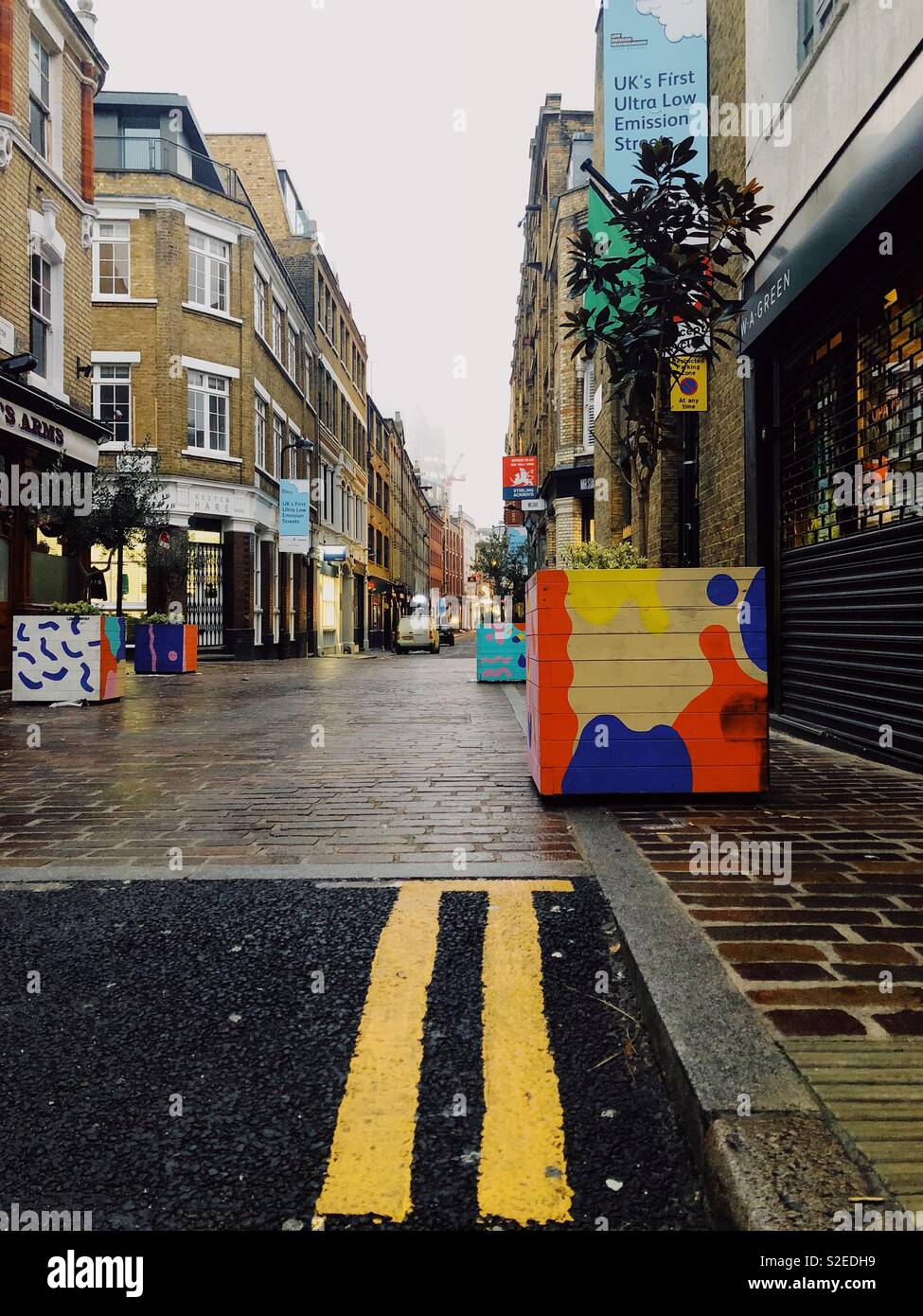 Charlotte Straße in Shoreditch, London, England. Bunte Pflanzmaschinen von Street Artists. UKs erste low emission Straße. Doppelten gelben Linien sind sichtbar auf der Asphaltstraße Stockfoto
