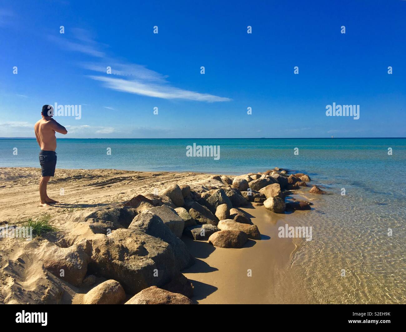 Mann in Shorts mit Blick aufs Meer in der Mornington Peninsula Victoria Australien - Smartphone-aufgenommenes Stockfoto