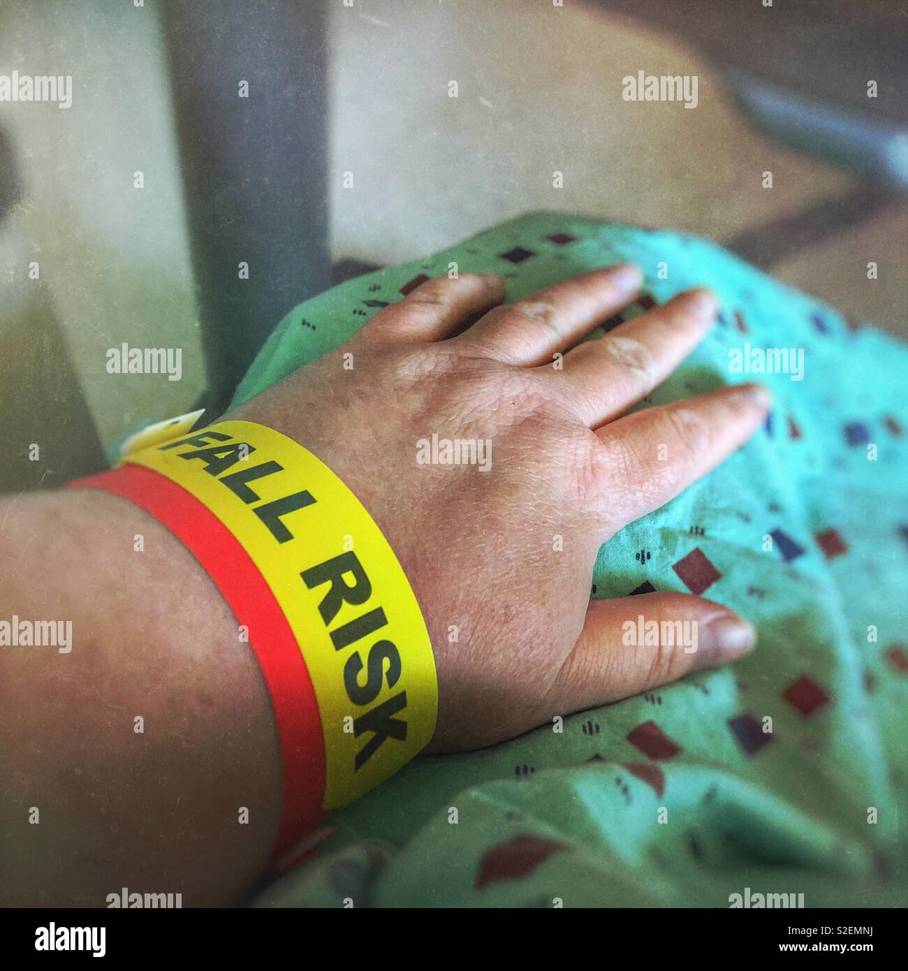 Eine Frau, trug einen Patientenkittel, hat einen Sturz risiko Armband auf ihren Arm. Stockfoto