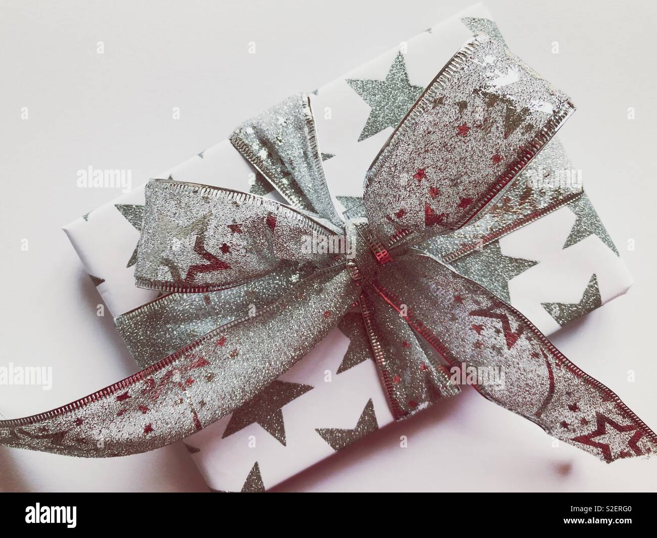 Weihnachtsgeschenk mit einem silbernen Band in eine extravagante Masche gebunden - Smartphone-aufgenommenes Stockfoto