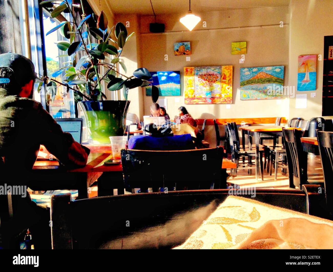 Hellen morgen Foto von Seattle coffeeshop Interieur, mit Gemälden an den Wänden und die Kunden in Ihren elektronischen Geräten absorbiert - Smartphone-aufgenommenes Stockfoto