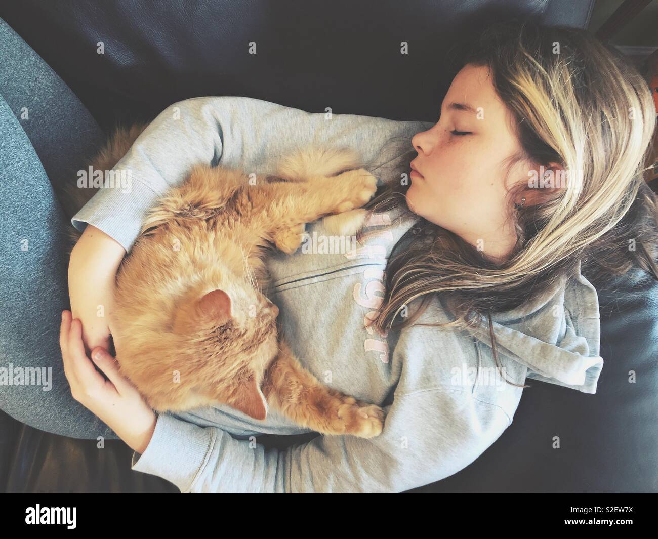 Mädchen Kuscheln und Schlafen mit orange Pet cat Stockfoto