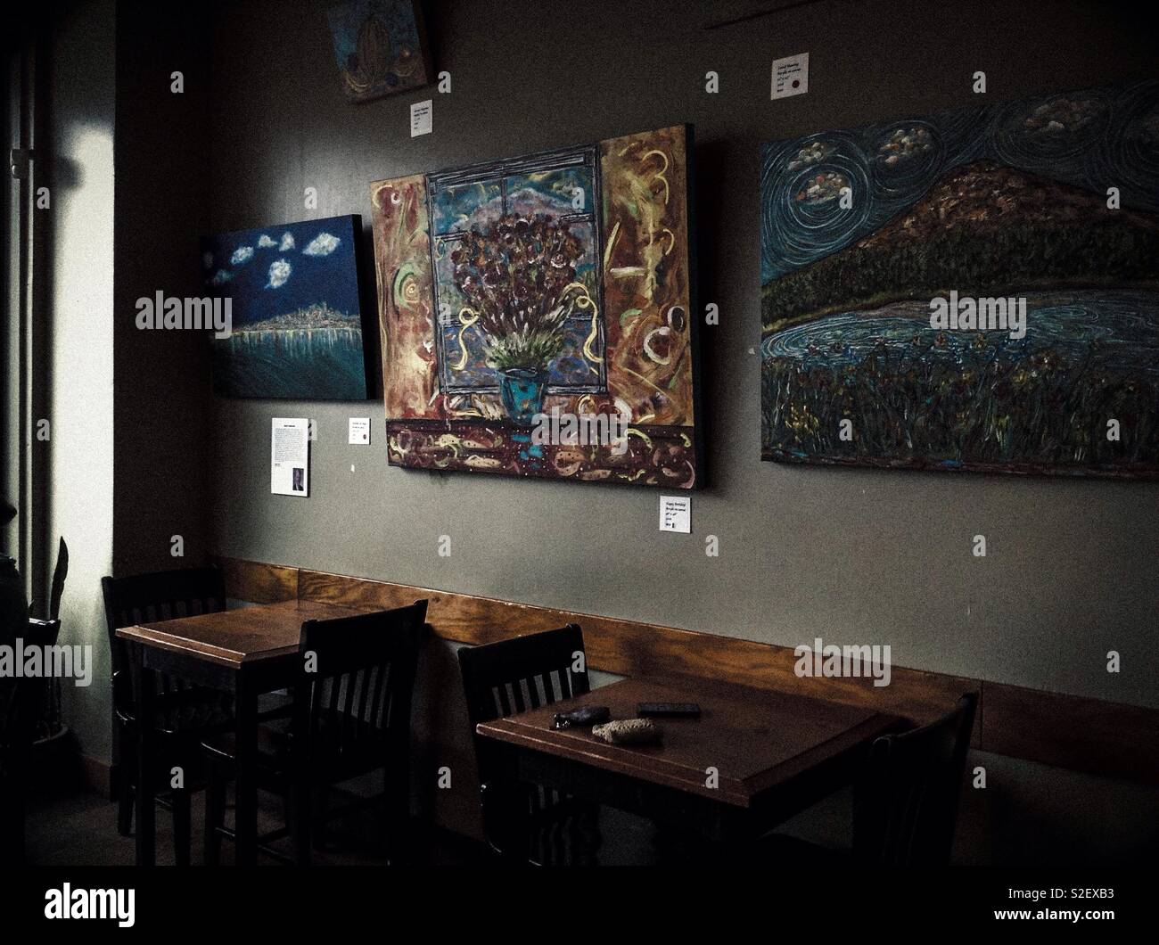 Gemälde an der Wand eines Seattle Coffeeshop, mit Holztischen und Stühlen - Smartphone-aufgenommenes Stockfoto