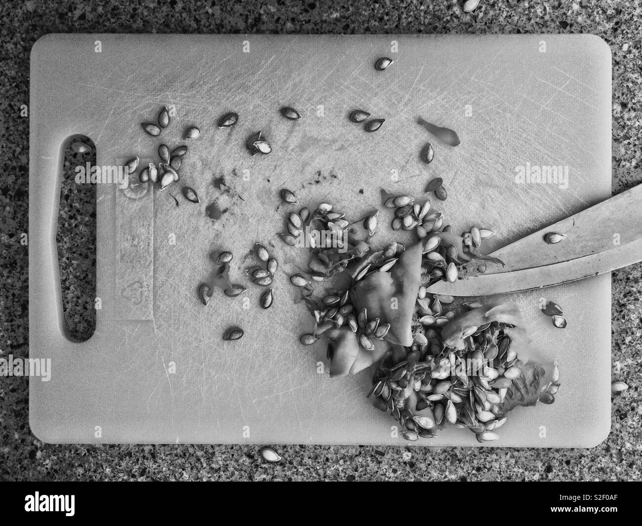 Pulp Küche: Schwarz und Weiß Foto von küchenarbeitsplatte mit Schneidebrett und Fruchtfleisch und Samen Butternut-kürbis mit Messer. - Smartphone-aufgenommenes Stockfoto