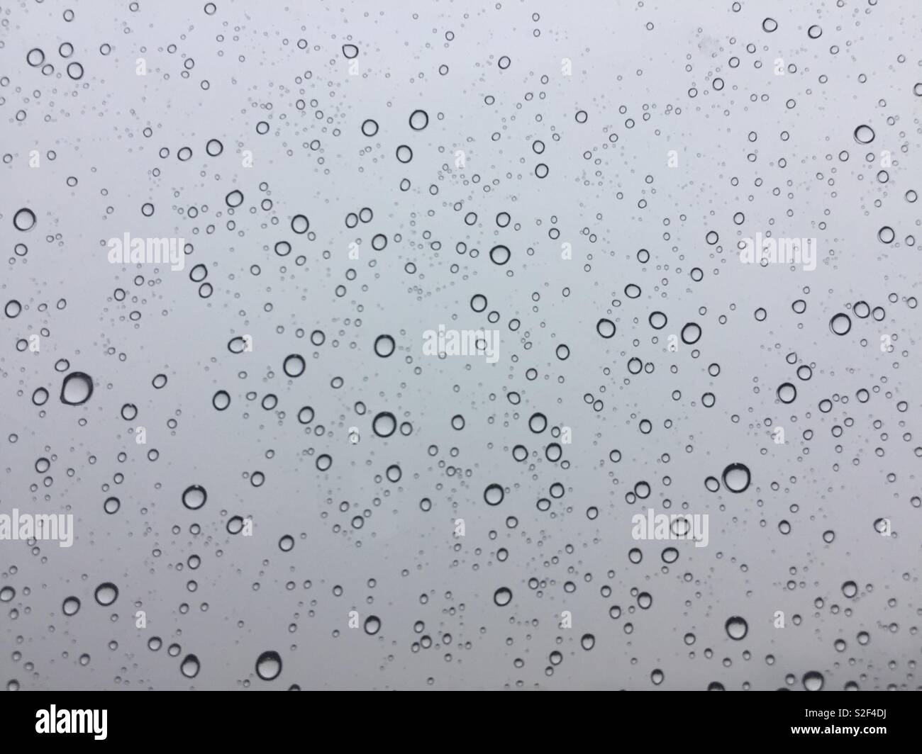 Regentropfen auf Glas mit einem grauen Himmel Stockfoto