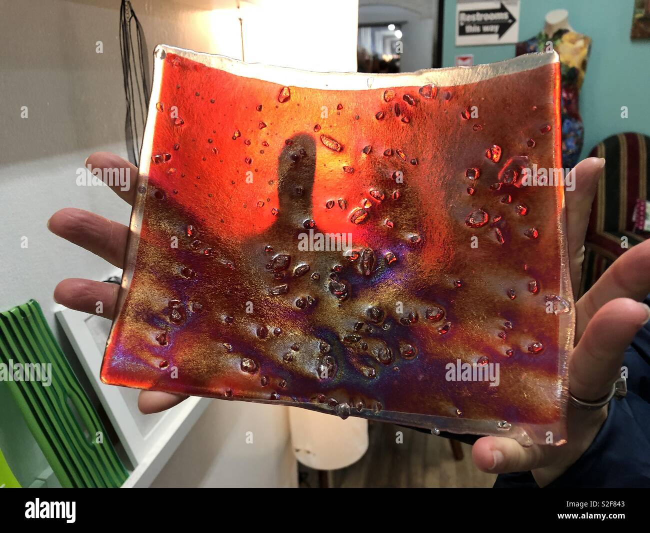 Irisierend rot Glas handgefertigte Servierplatte in Händen an Artist's Studio statt Stockfoto