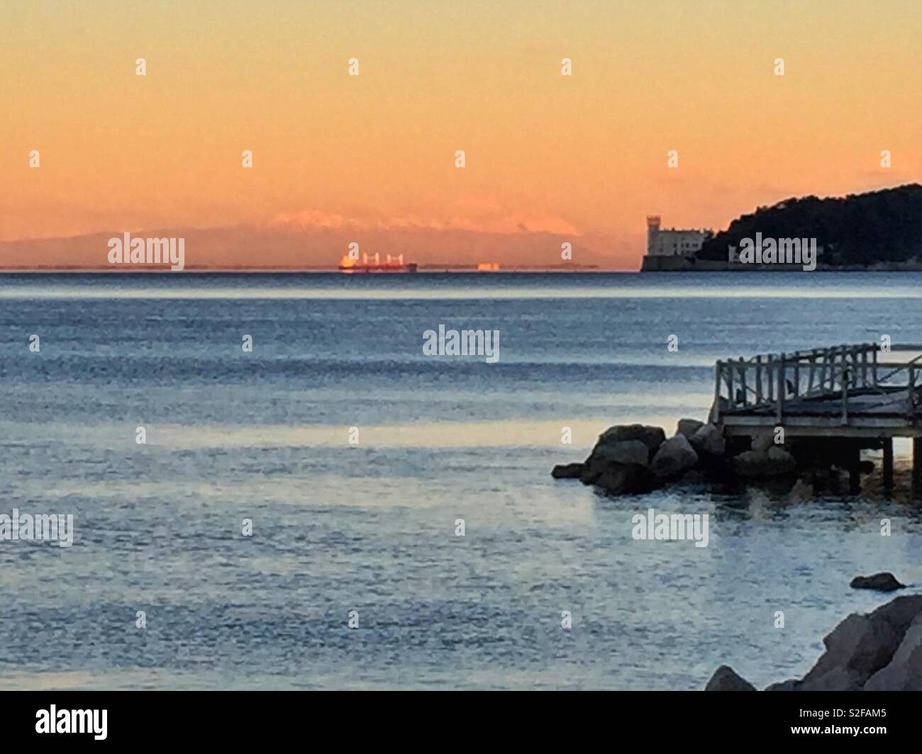 Berge und das Schloss Miramare in der Morgendämmerung. Triest, Italien. - Smartphone-aufgenommenes Stockfoto