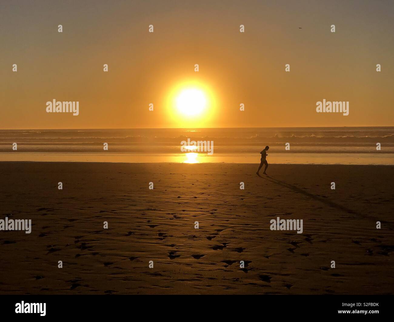 Silhouette runner am Strand bei Sonnenuntergang laufen Stockfoto