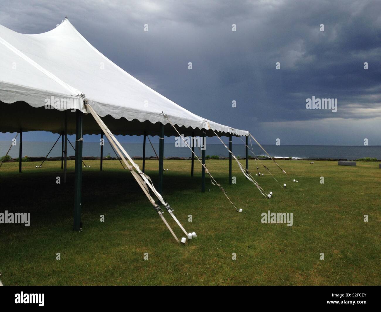 Ein weißes Zelt mit dunklen Gewitterwolken über den Ozean im Sommer Stockfoto