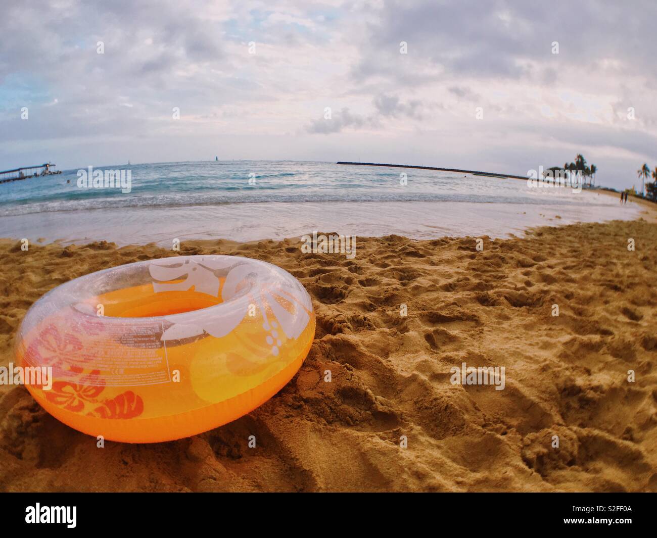 Aufblasbare gelb Schwimmring float auf dem Sand sitzt auf einem Hawaiian Beach an einem bewölkten Tag. Stockfoto