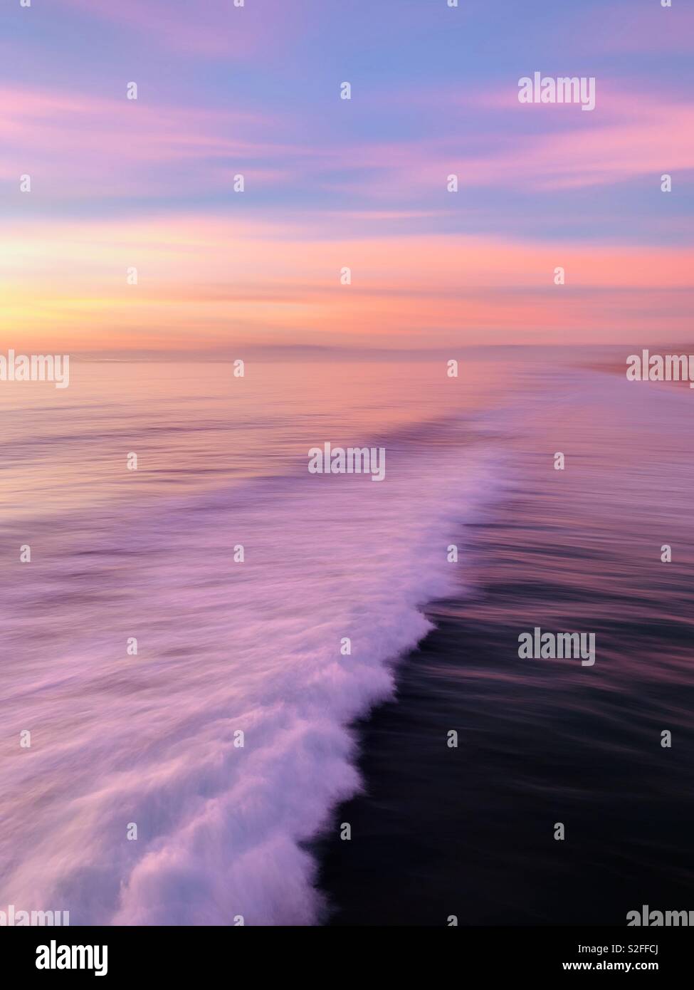 Die Unschärfe der eine Welle bricht bei Sonnenuntergang. Manhattan Beach, Kalifornien, USA. Stockfoto