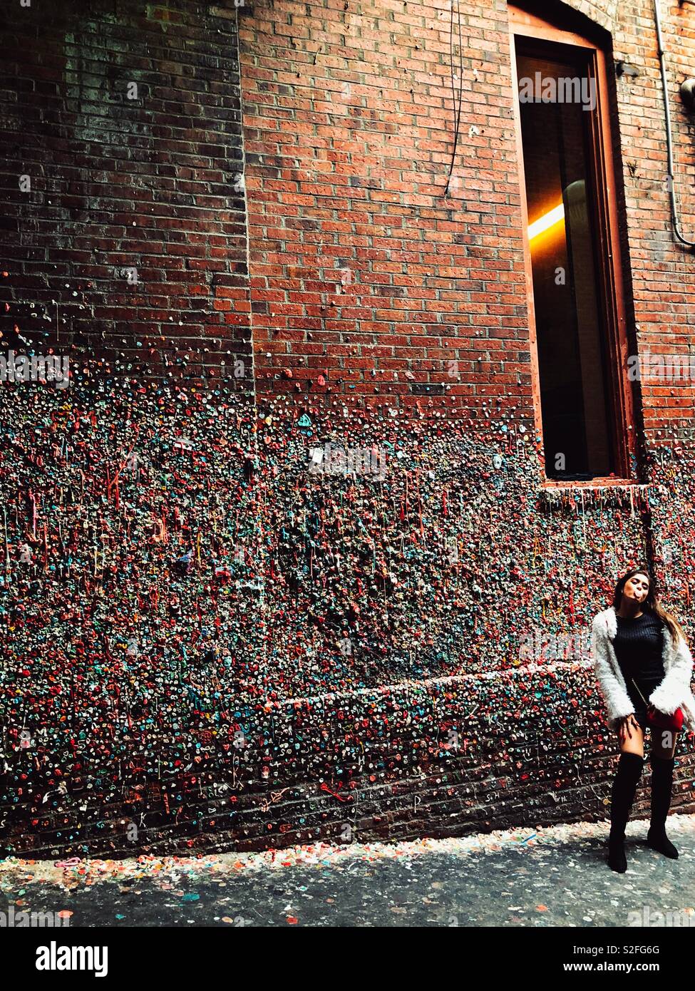 Junge Frau blasen Bubble Gum vor Gummi abgedeckt Wand in Post-Gasse in Seattle. Stockfoto