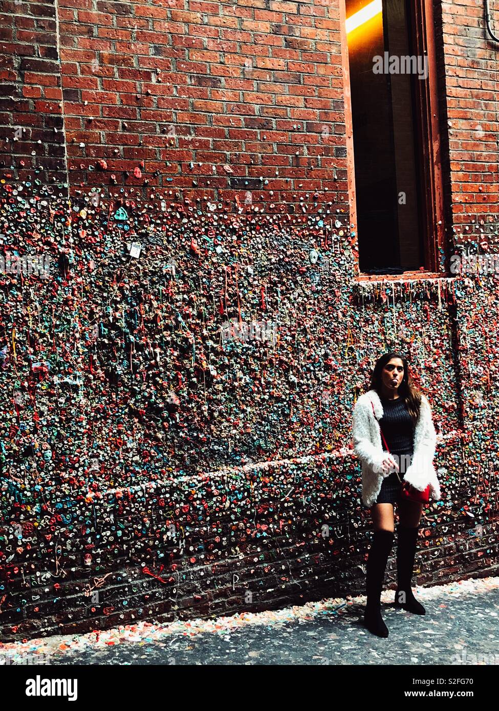 Junge Frau blasen Bubble Gum für Foto opp vor Gummi abgedeckt Wand in Post-Gasse in Seattle. Stockfoto