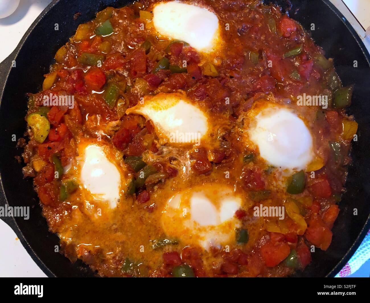 Das Mittelmeer Teller, shakshouka oder Shakshuka - pochierte Eier in einer Sauce aus Tomaten, Paprika und Zwiebeln mit Gewürzen und Knoblauch Stockfoto