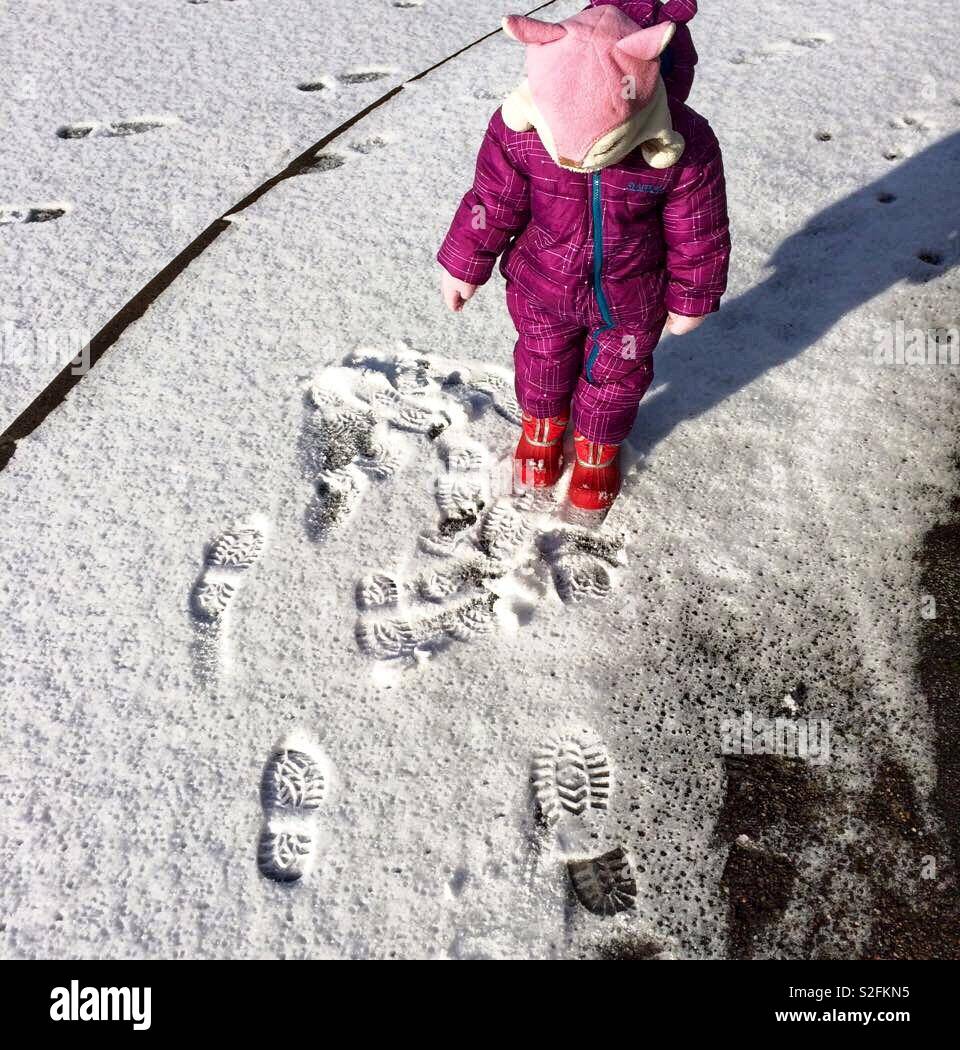 Kleinkind auf eigenen Spuren im frischen Schnee Stockfoto