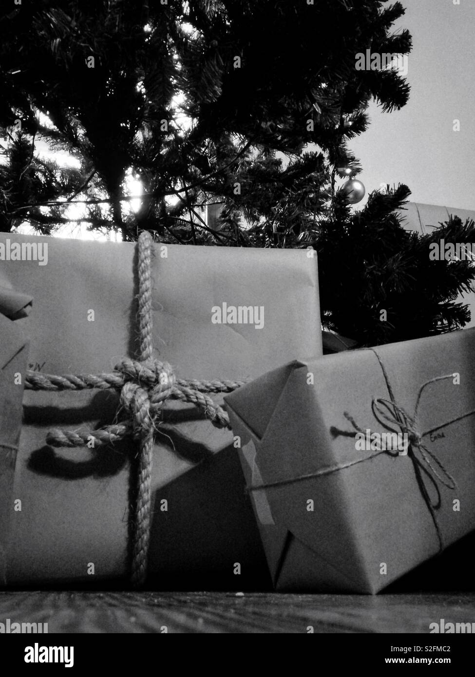 Gestochen scharfe Schwarz-Weiß-Foto Papier verpackt Geschenke unter dem Weihnachtsbaum mit string und Seil gebunden Stockfoto