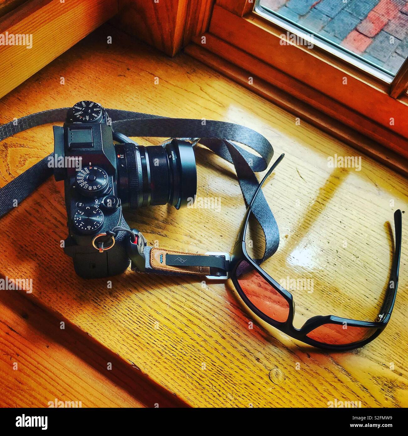 Fujifilm XT2 mit XF 23-mm-Objektiv und Smith Sonnenbrille auf einer sonnigen Fensterbank. Stockfoto