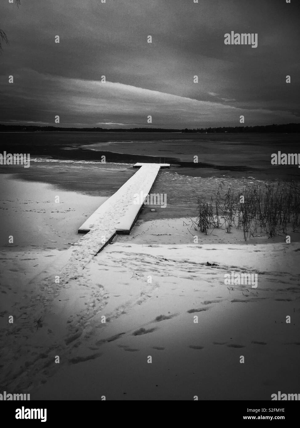 Schnee bedeckt Pier auf der semi frozen lake Stockfoto