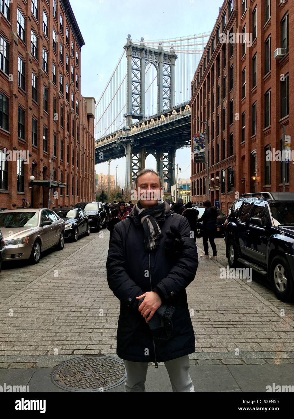 Mann auf der Straße mit Kopfsteinpflaster an DUMBO (Down Under Manhattan Bridge Überführung), Brooklyn, mit Loft wohnen und Manhattan Bridge im Hintergrund. Stockfoto