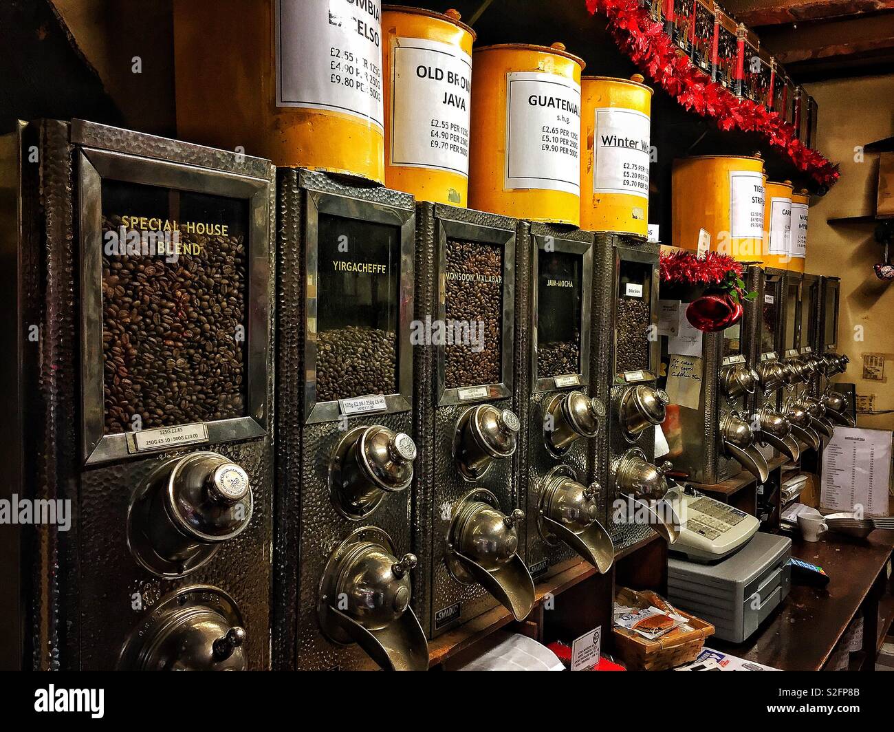 Vintage Kaffeespender mit einer Auswahl an Kaffeebohnen in einem Geschäft, die Tradition mit Kaffeespezialitäten für Kaffeeliebhaber kombinieren - Smartphone-aufgenommenes Stockfoto