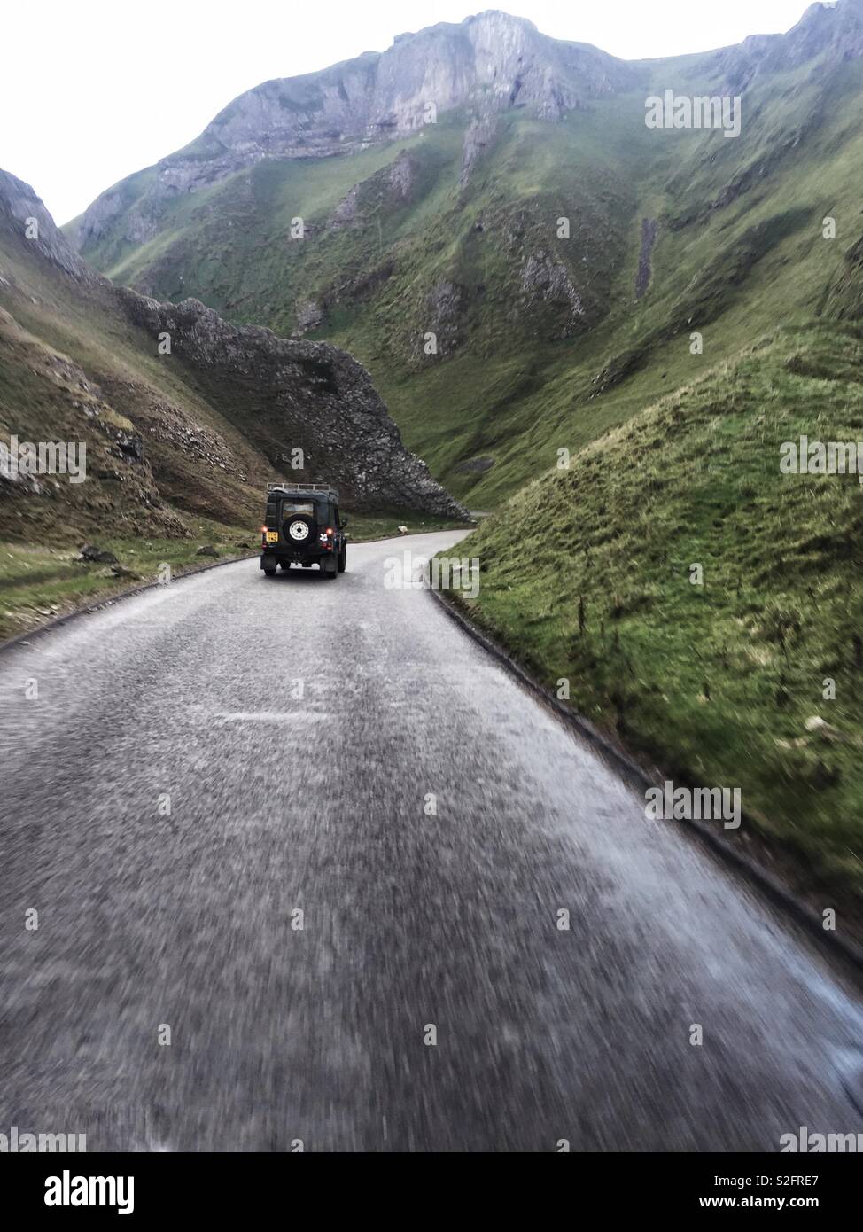 Auf der Suche einer bergigen Straße als Land Rover fährt bergab durch unwegsames Gelände Stockfoto