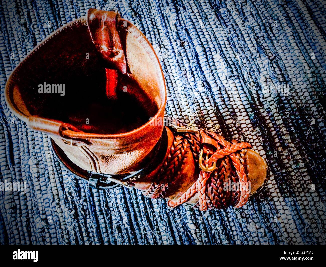 Cowboy-stiefel auf blauen geflochtenen Teppich in Leder Gürtel gewickelt zu  spannen während der Kleber trocknet reparieren Stockfotografie - Alamy