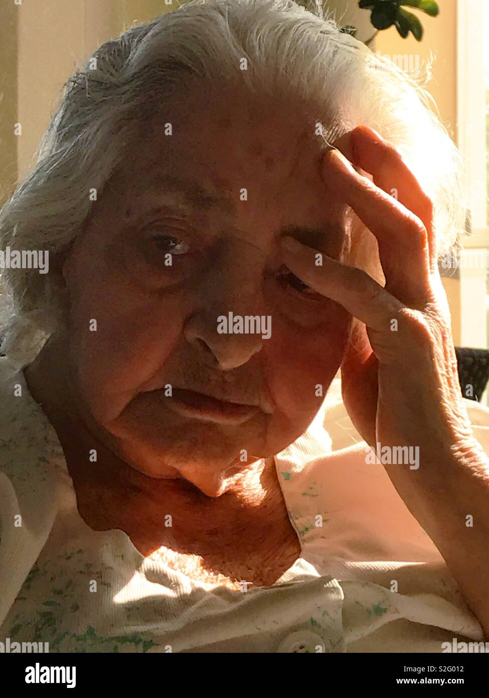 Porträt der alten Frau, die Hand auf den Kopf. - Smartphone-aufgenommenes Stockfoto