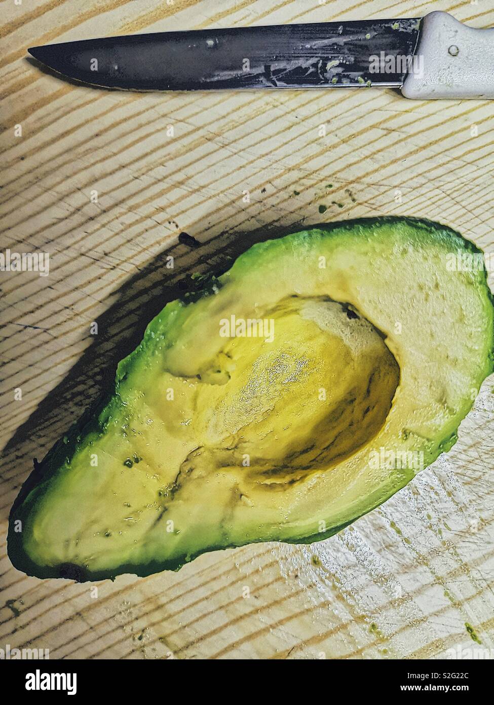 High Angle Shot eine halbe Avocado auf Schneidebrett mit Messer - Smartphone-aufgenommenes Stockfoto