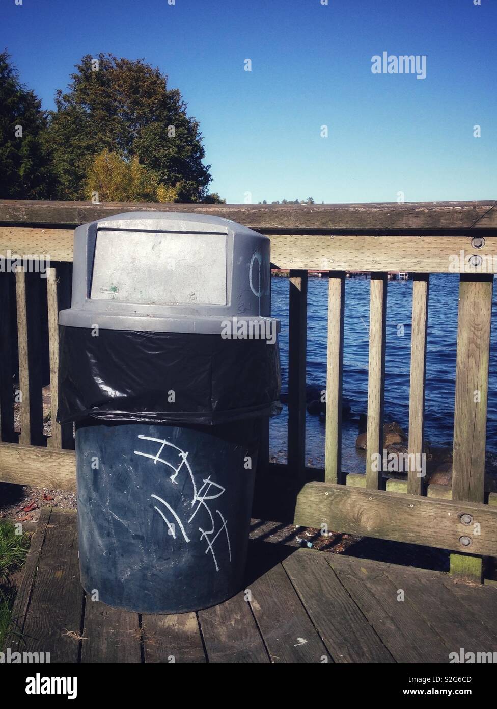Mülleimer durch Geländer auf Lake Washington, Seattle, mit Inri graffitied auf Seite Stockfoto