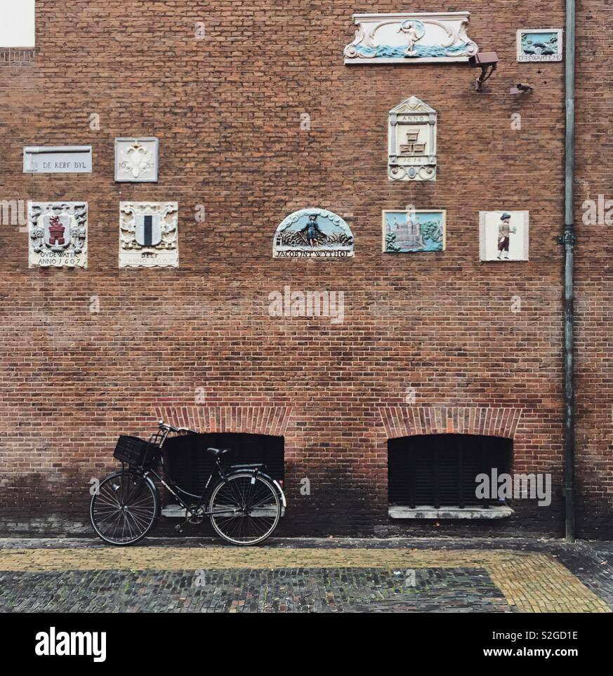 Wall Plaques und ein Fahrrad gegen eine Mauer in Amsterdam - Smartphone-aufgenommenes Stockfoto