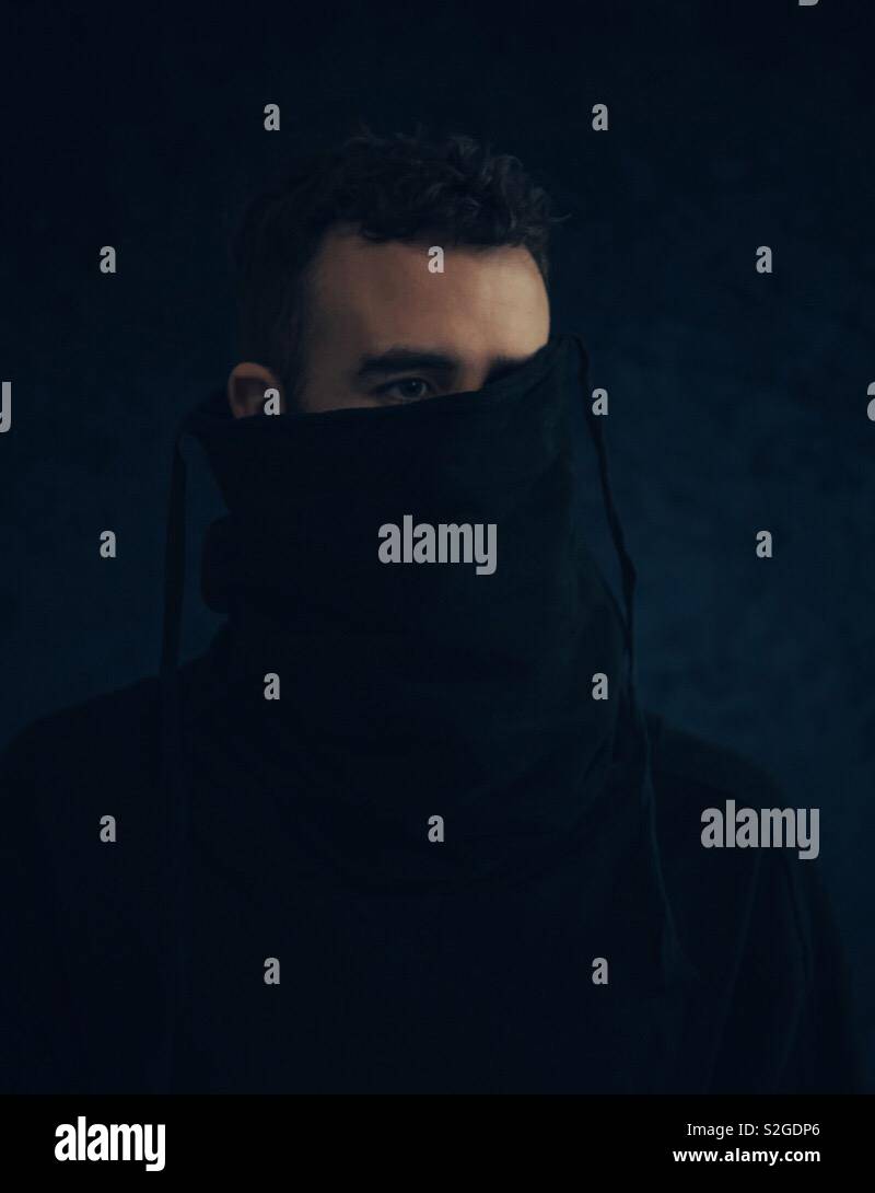 Mann versteckt sich in seinem Pullover von der Kamera nicht zu seinem Bild. - Smartphone-aufgenommenes Stockfoto