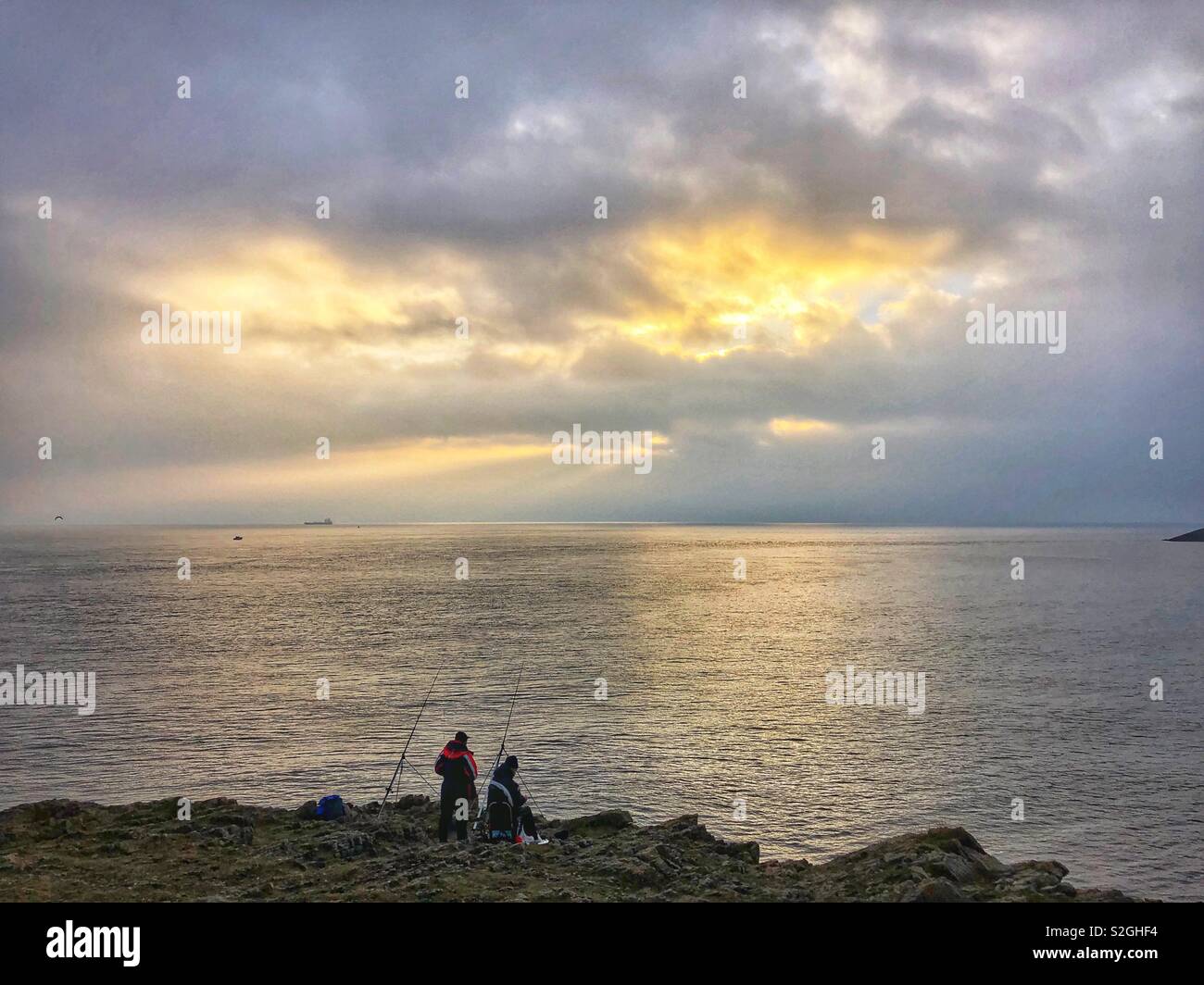 Zwei Fischer aus Felsen bei Dämmerung in Barry, South Wales. Stockfoto