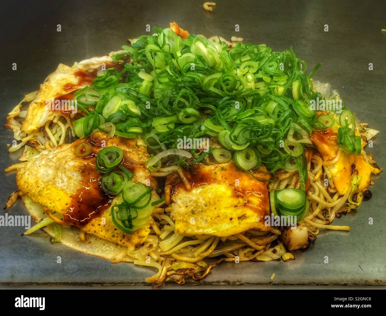 Ein frisch zubereitetes Hiroshima Okonomiyaki auf einer Heizplatte Stockfoto