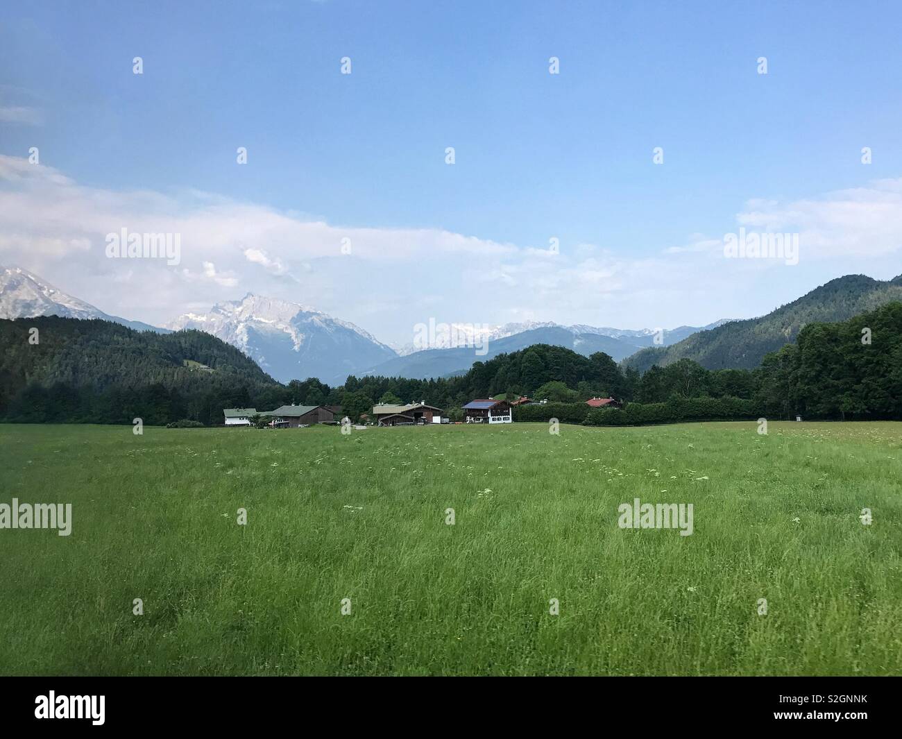Die üppige, grüne Landschaft Österreichs, in der Nähe der deutschen Grenze und mit der östlichen Alpen im Hintergrund dargestellt ist, wird an einem sonnigen Tag gezeigt. - Smartphone-aufgenommenes Stockfoto