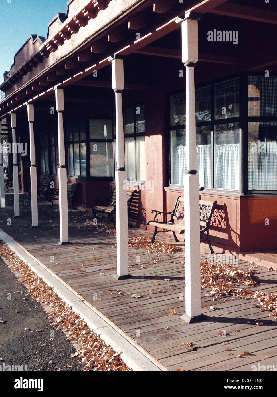 Blätter im Herbst Streuung über holzbrett Gehweg auf alten Westen suche Storefront - Smartphone-aufgenommenes Stockfoto