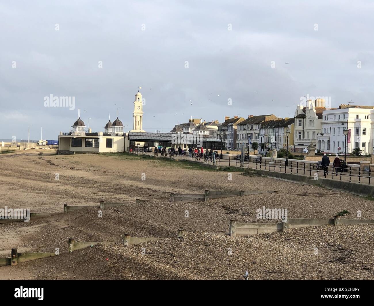 Der Strand und das Meer in Herne Bay, Kent mit dem Pavillon und Clock Tower, mit Besuchern und Möwen im hellen Sonnenschein. Stockfoto