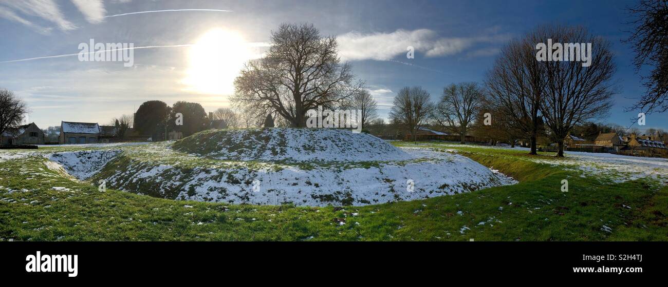Panorama der rätselhaften Überreste eines kleinen normannischen Motte und Bailey Schloss herausgesucht, die von Winter Schnee und Eis begraben, aber wie ein UFO bei Guiting Power in den Cotswolds. - Smartphone-aufgenommenes Stockfoto