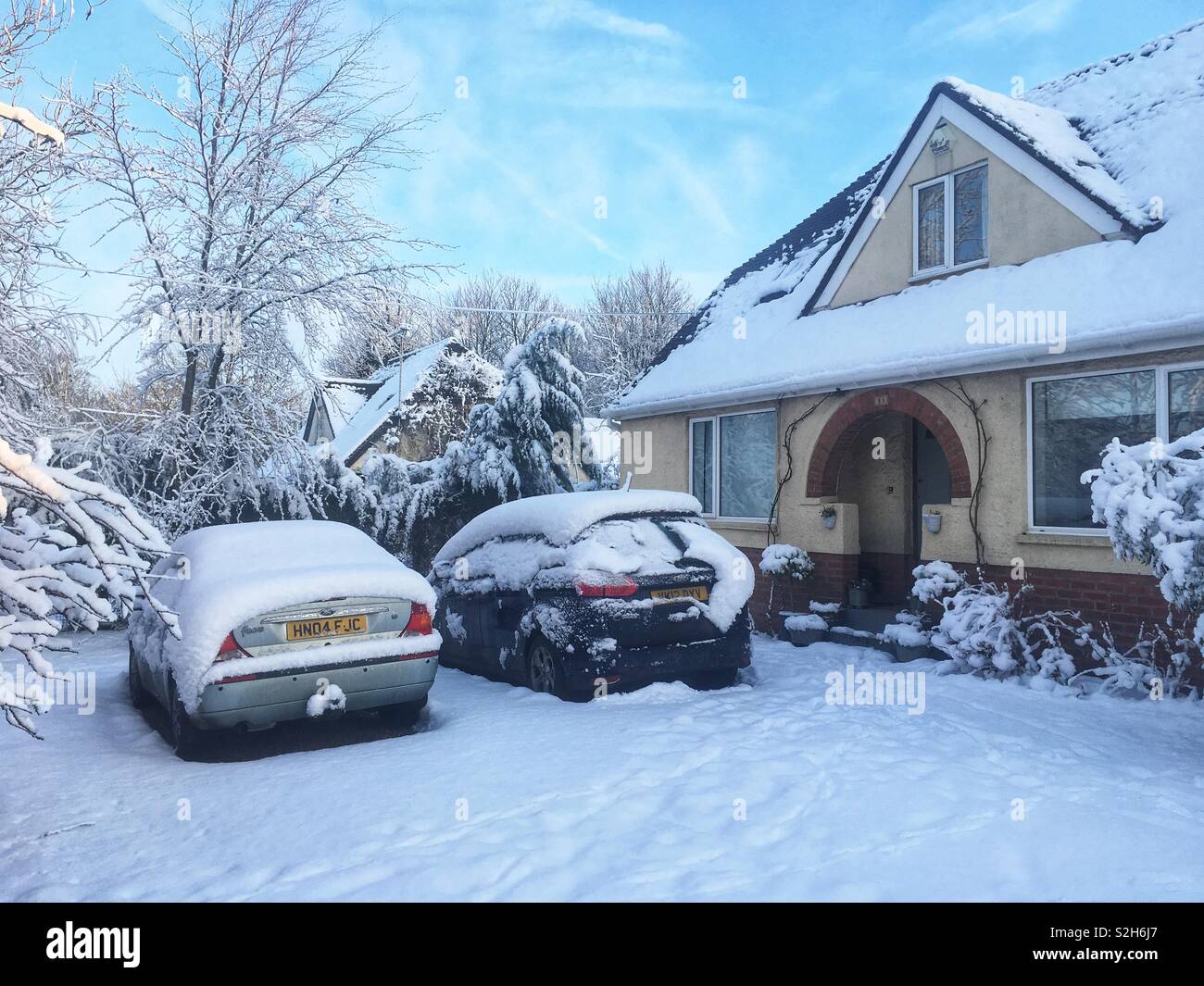 Verschneite Einfahrt mit Autos im Schnee, Hampshire, England, Vereinigtes Königreich. - Smartphone-aufgenommenes Stockfoto