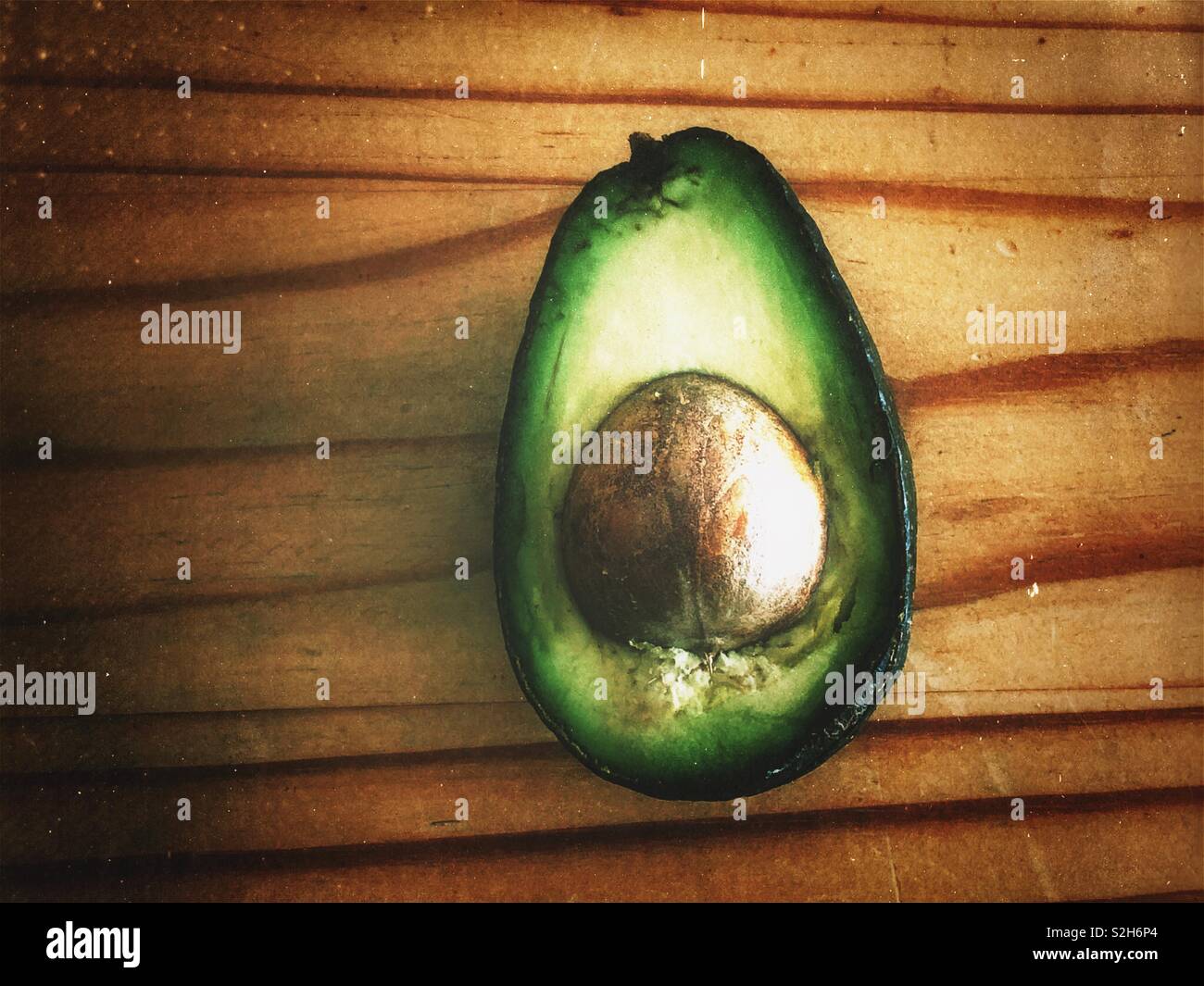 Rustikale Bild von eine halbe Avocado mit Grube auf Holz- Oberfläche - Smartphone-aufgenommenes Stockfoto